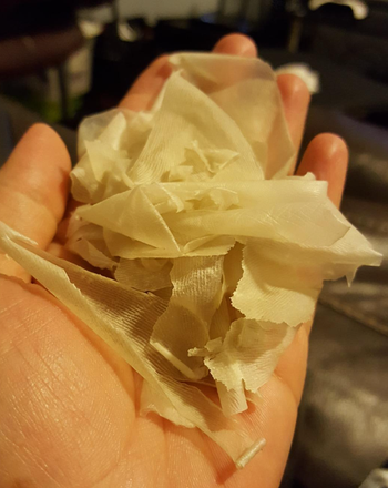 Another reviewer proudly holds up the dead skin that has peeled off after using the foot mask, showcasing the results.