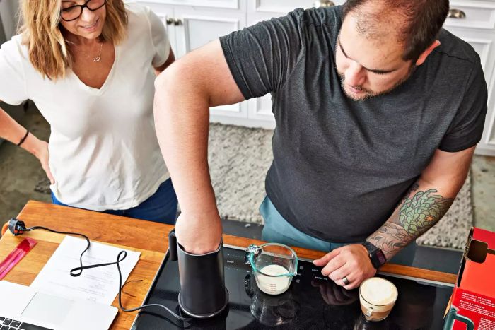 A person inserting their hand into the Instant Pot Instant Milk Frother while another person observes