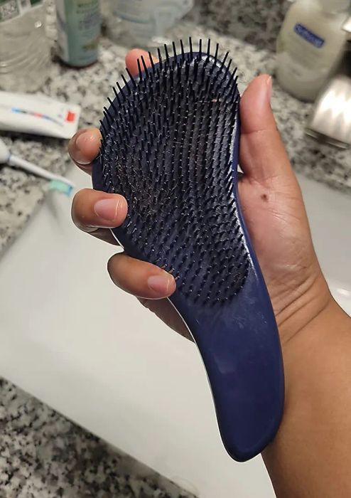 a reviewer holding the detangling brush