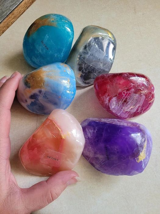 A variety of decorative soaps in colors like blue, black, red, pink, and purple, each carefully labeled for display.