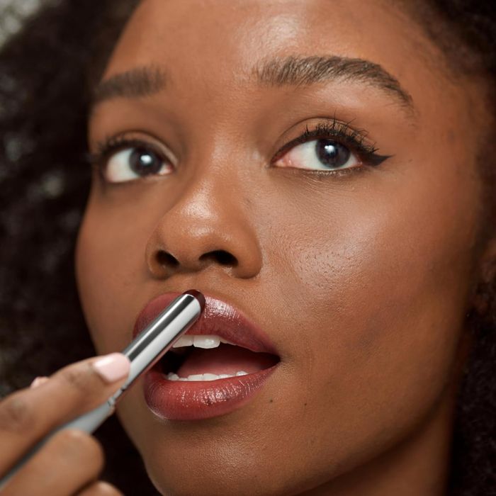 A person applying the Clinique lipstick to their lips, focusing on the product