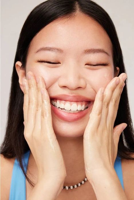 The model applying the cleanser to their skin