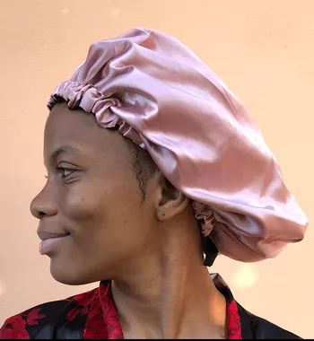 A person wearing a smooth, shiny silk bonnet looks to the left, offering a slight smile.