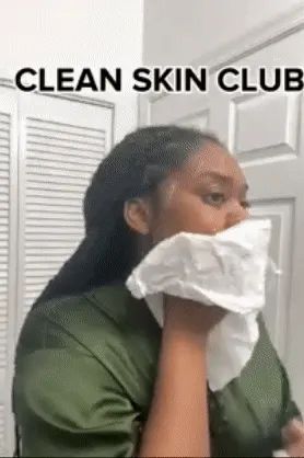 A reviewer using a white towel to gently clean their face.