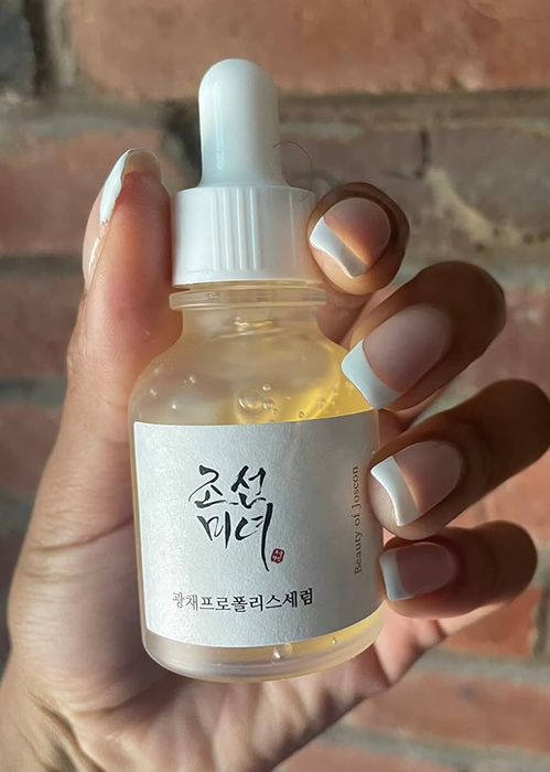 A hand holding a bottle of Beauty of Joseon Glow Serum.