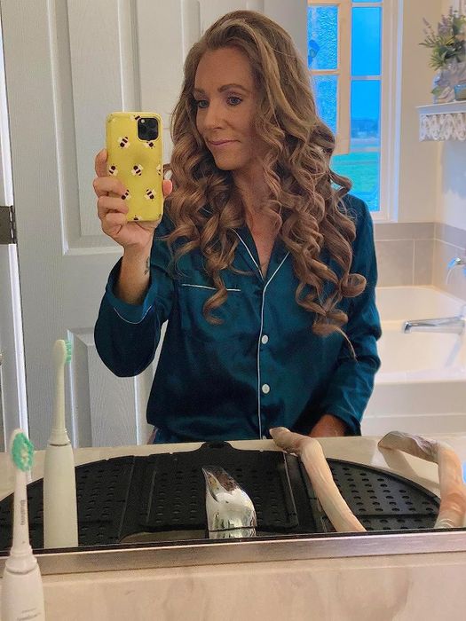 A reviewer showing off their soft, bouncy curls after using the satin heatless curlers overnight