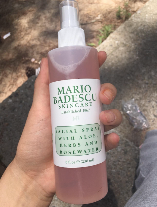 Reviewer holding a pink bottle of facial spray