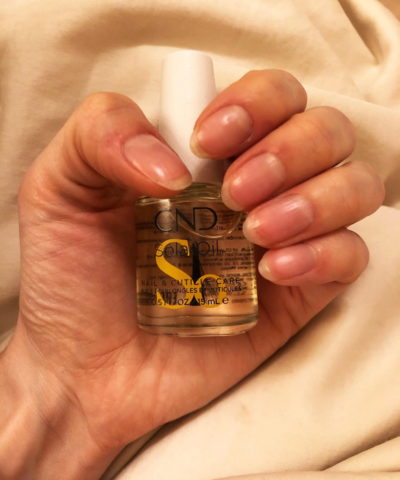 Another reviewer photo holding the bottle, showcasing healthy, long nails
