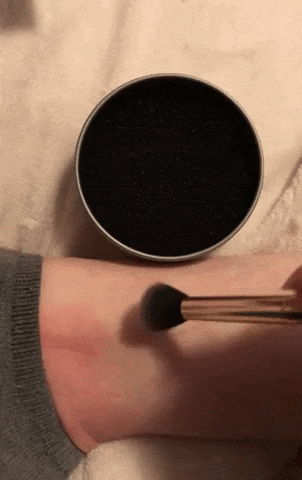 GIF demonstrating an eyeshadow brush applying pigment to an arm, then cleaning it in the sponge for a few seconds, and wiping the arm to show no residue left