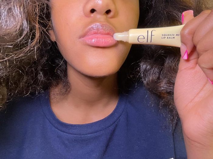A reviewer holding the lip balm next to their lips