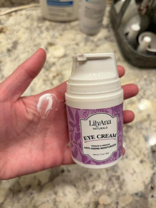A reviewer holding a bottle of eye cream.