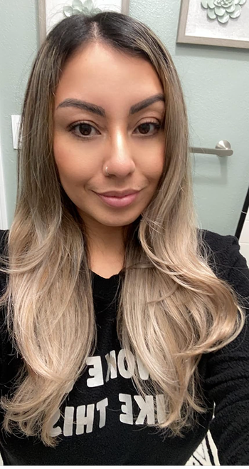 A reviewer shows off their medium-length hair, styled with soft curls at the ends.