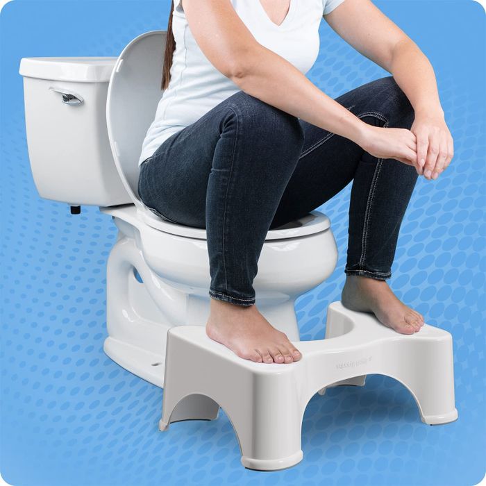 Model sitting on the toilet with their feet placed on the Squatty Potty