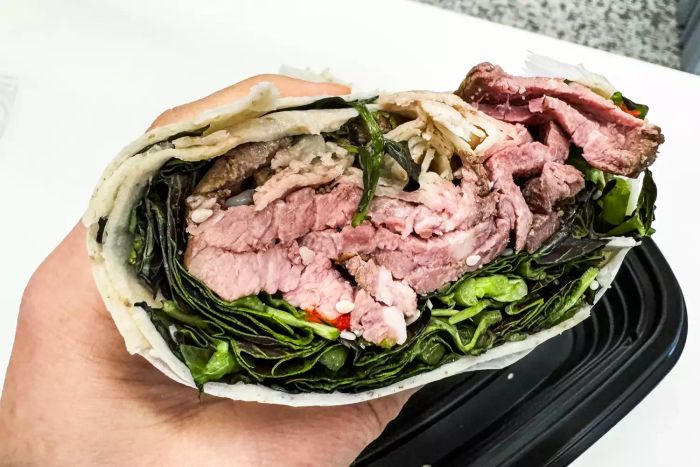 A hand holding a wrap from the Epicured meal box