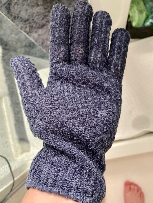 Reviewer wearing blue exfoliating gloves while in the shower
