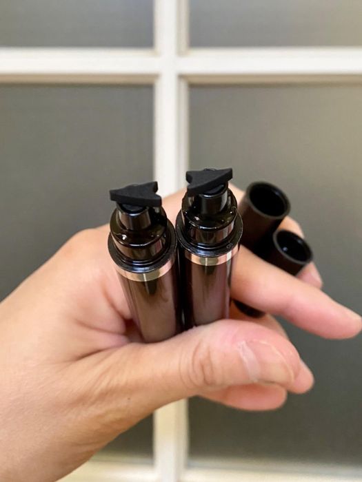 A reviewer holding two eyeliner stamps, each featuring a slightly curved tip designed to add a winged effect to black eyeliner