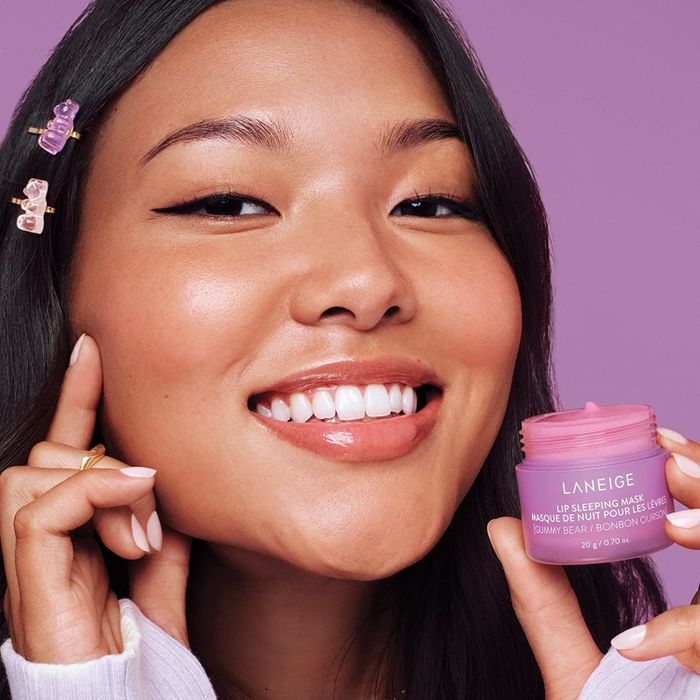 The same model now holding the small pink tub of Laneige Lip Sleeping Mask in Gummy Bear.