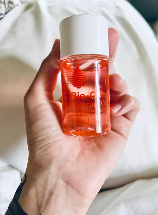 A hand holding a small bottle of Bio-Oil skincare product