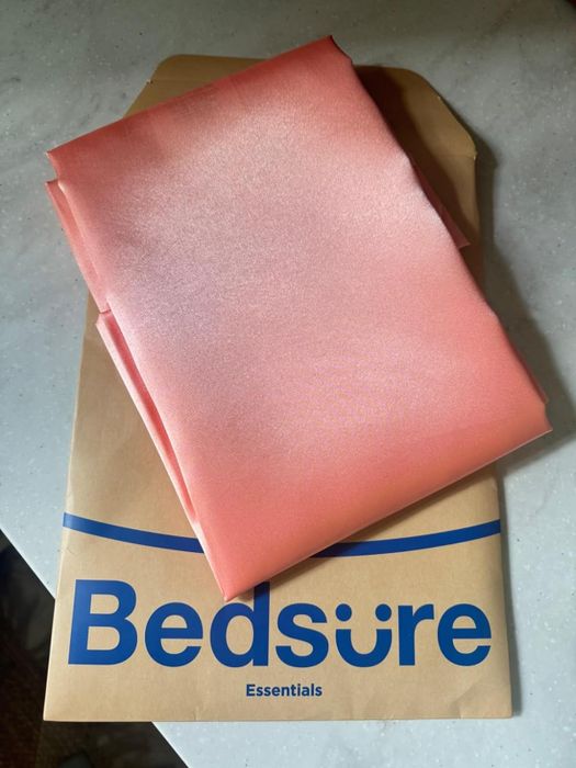 A folded Bedsure Essentials satin pillowcase placed neatly on top of its branded packaging.