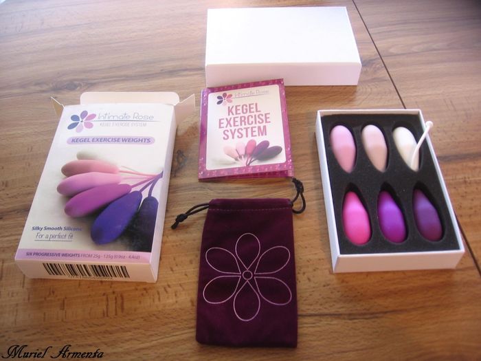 A collection of Kegel exercise products from Intimate Rose, featuring various colored weights, a pouch, and a box labeled with the brand name.