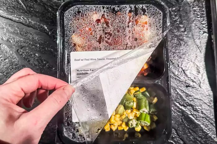 A person peels the plastic off the Magic Kitchen meal.