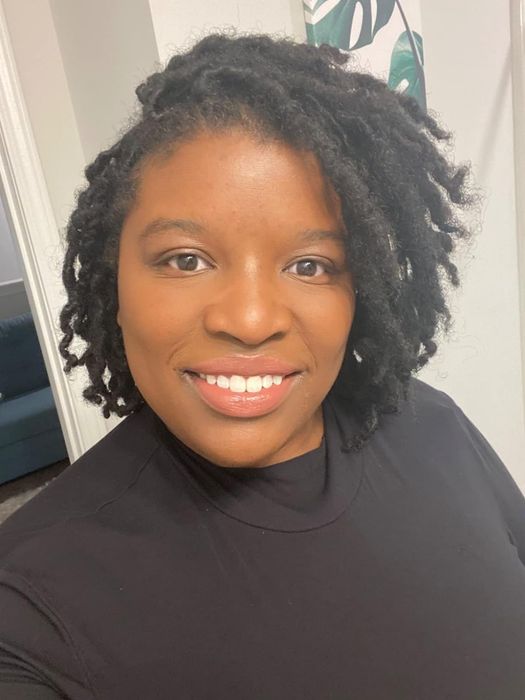 A reviewer with darker skin wearing a nude-colored lip product.
