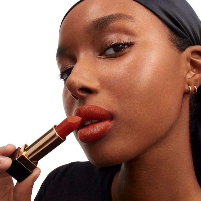 A model applying a bold red YSL lipstick