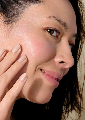 A model massaging sunscreen into their cheek.