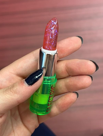 A reviewer holding a pink glittery lipstick tube.