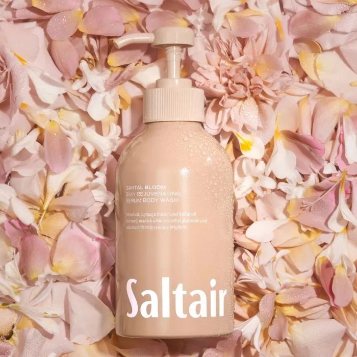 Saltair's Santal Bloom Skin Rejuvenating Serum Body Wash bottle surrounded by soft, blooming flower petals.