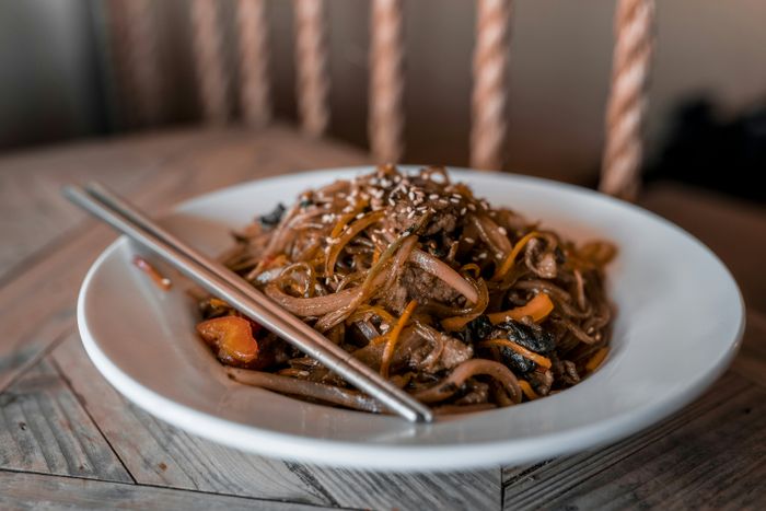 A brown and white ceramic bowl accompanied by brown and white chopsticks
