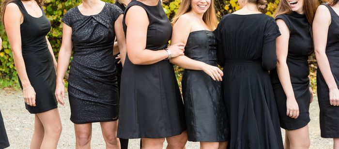 A group of women wearing black dresses, smiling and laughing at an outdoor wedding. Their names are unknown
