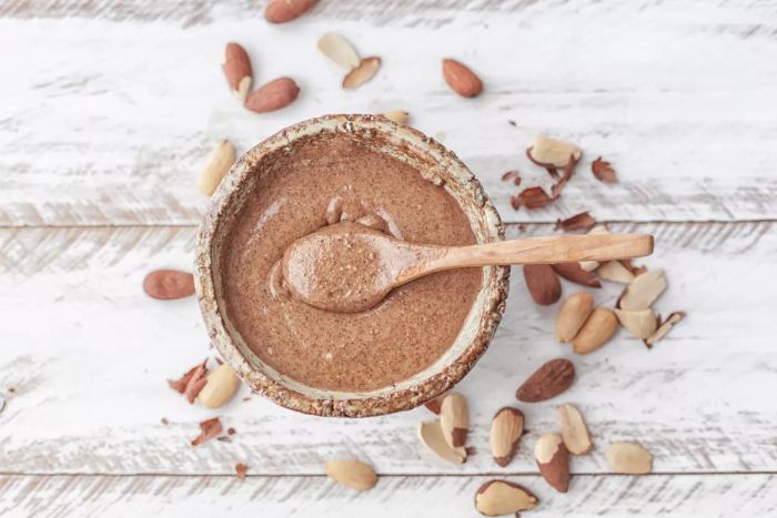 A top view of a jar of almond butter with a spoon resting on top
