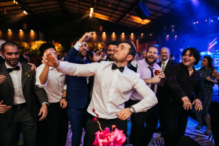 Guests dressed in formal attire enjoy dancing at a lively wedding reception, set in an elegant venue