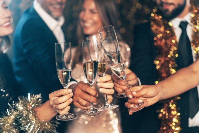 A group of people dressed in formal attire toasting with champagne glasses, celebrating at an extravagant event