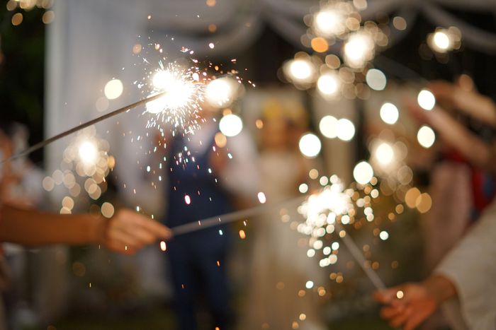 Wedding guests holding sparklers, creating a lively and cheerful ambiance during an evening celebration