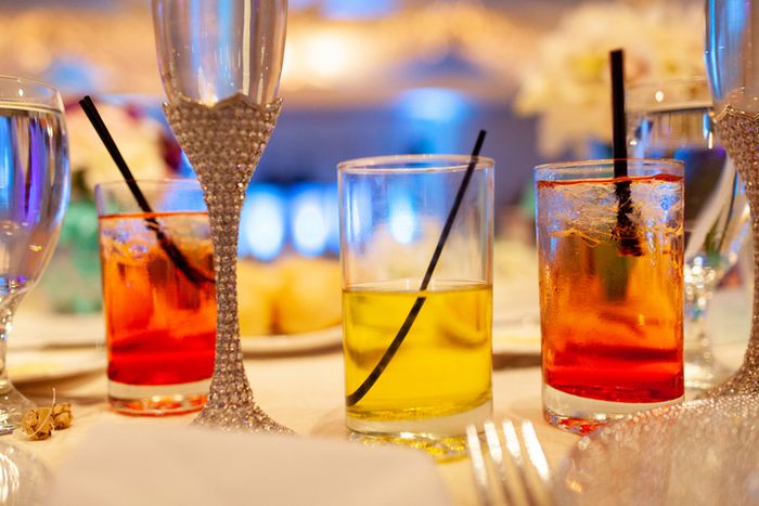A close-up of elegant champagne flutes and vibrant cocktails on a wedding reception table setting