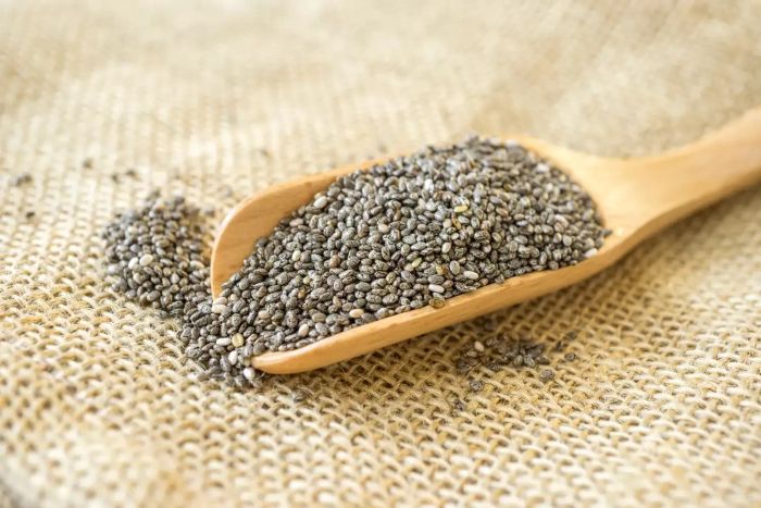 Chia seeds resting on a large wooden spoon