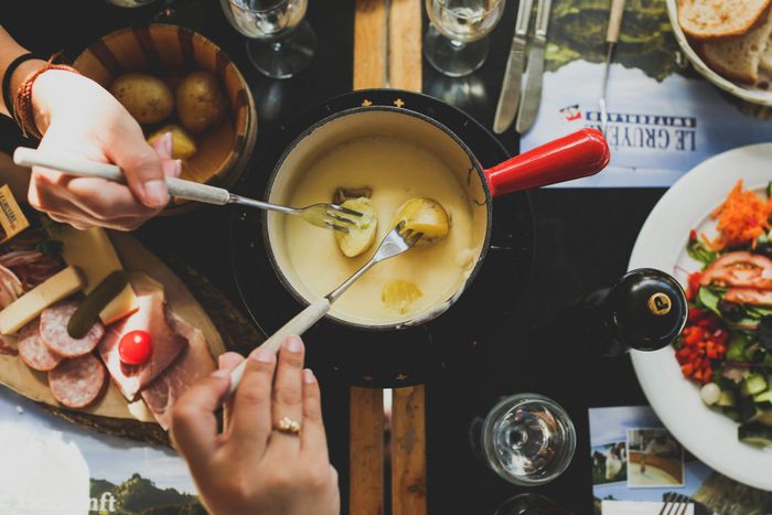 two people holding forks, dipping food into sauce