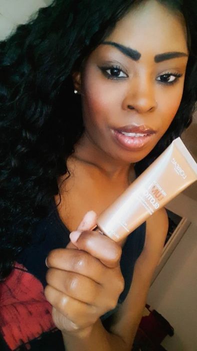 Reviewer wearing and holding L'Oreal Paris Makeup True Match Lumi Glotion
