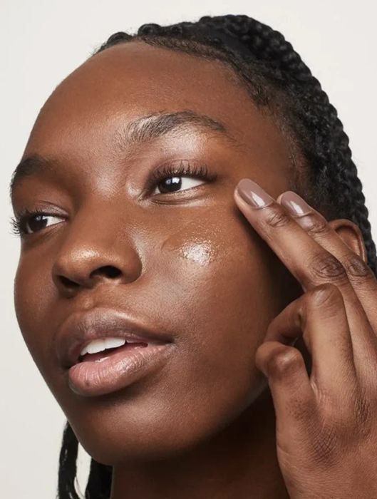 Model applying Glossier Perfecting Skin Tint to their skin