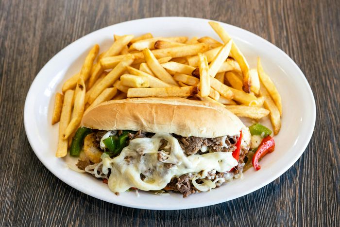 A white plate with a sandwich and fries on top