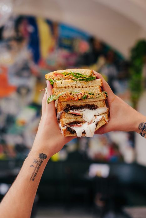 someone holding a burger with a patty and cheese