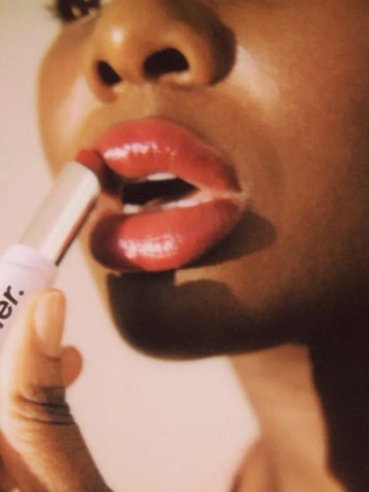 Model applying the Glossier Ultralip lipstick