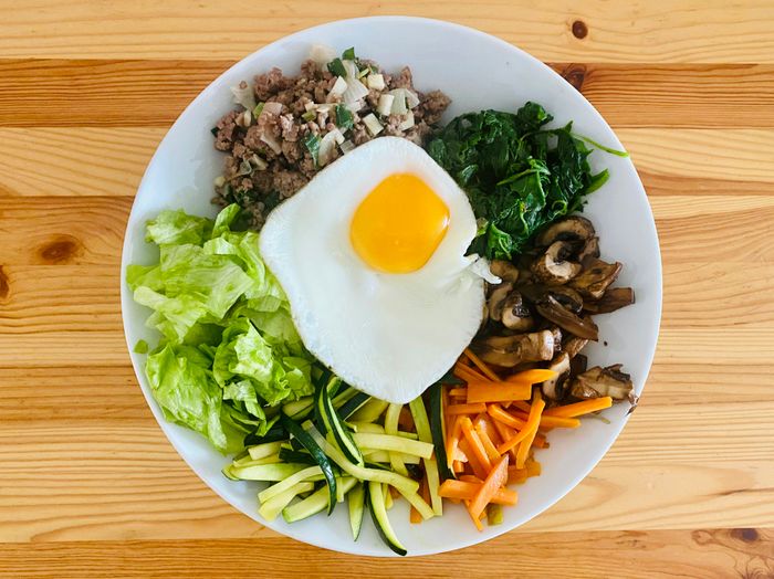A fresh egg resting on a white ceramic plate