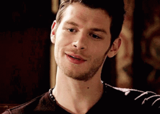 Klaus smiling softly to the side in a relaxed setting