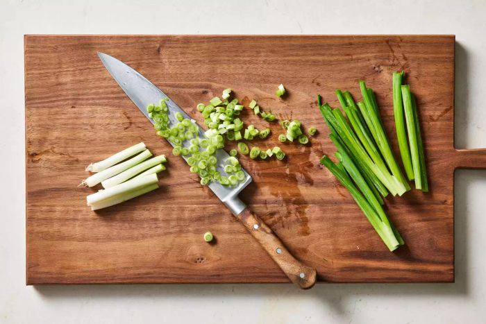 Scallions being sliced on a cutting board