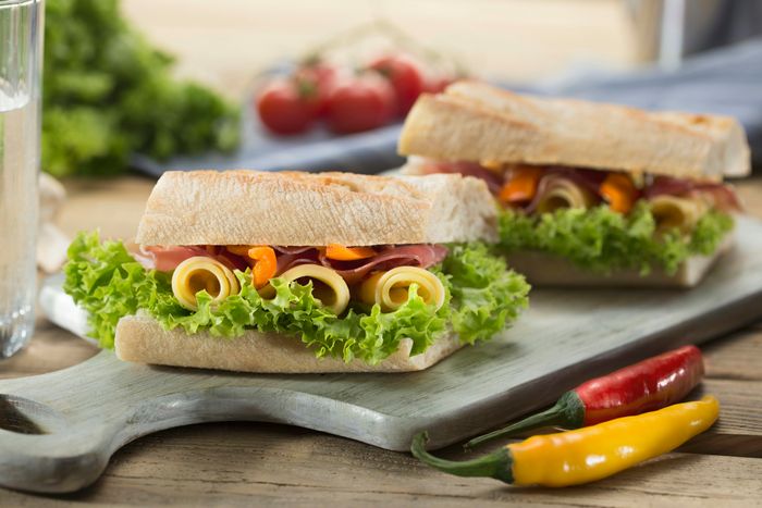 a sandwich filled with lettuce and cheese served on a chopping board