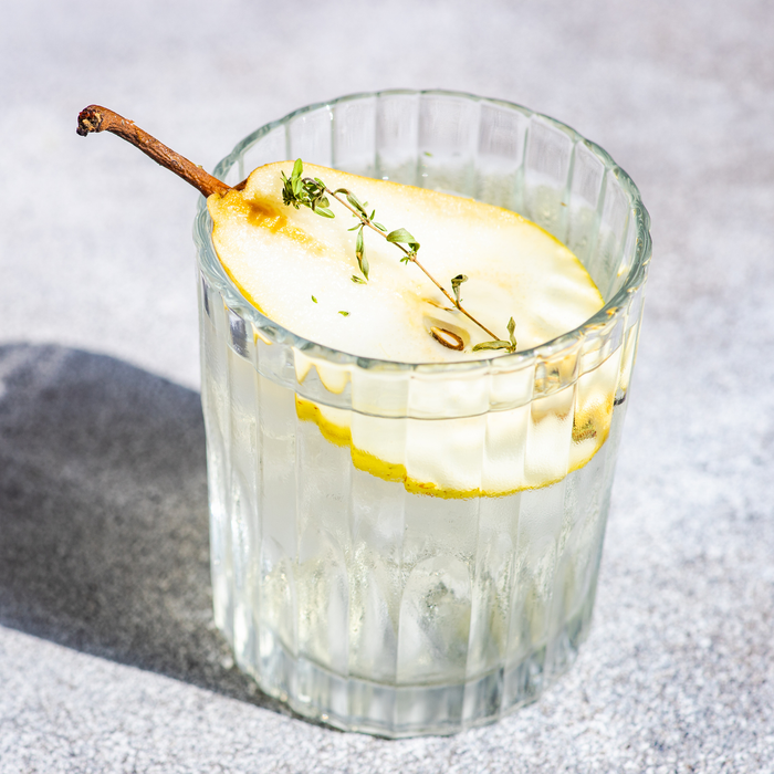 Pear vodka mixed with tonic, garnished with fresh pear slices and thyme