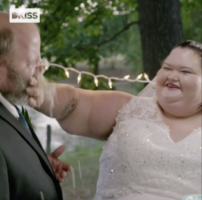 bride playfully applying cake to the groom's face